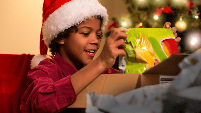 Boy smiling while opening a holiday gift of a coding program
